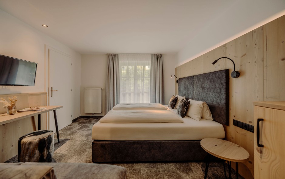 Ein modernes Hotelzimmer mit Doppelbett, Flachbildschirm und großen Fenstern