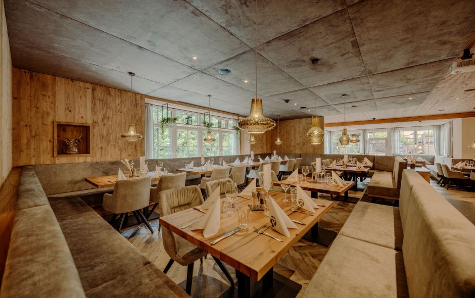 Gemütlicher Restaurantbereich mit Holzakzenten, Polstersitzen und modernen Lampen