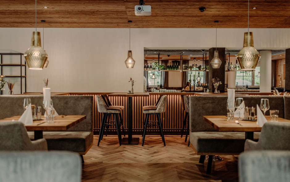 Stilvoll eingerichtetes Restaurant mit Holzdekor und gedeckten Tischen im Resl Resort