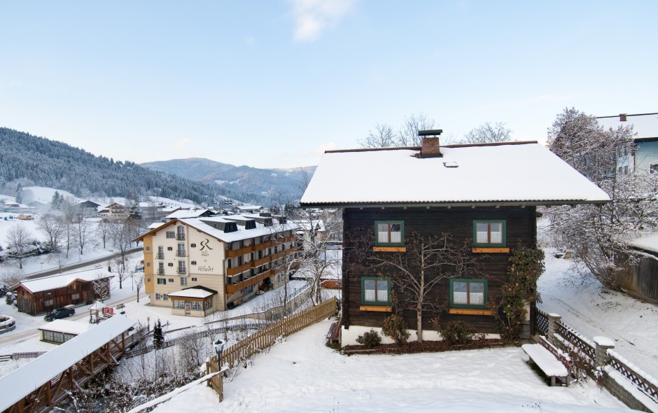 Schneiderhäusl im Winter - verschneite Außenansicht mit Hotel Resl im Hintergrund