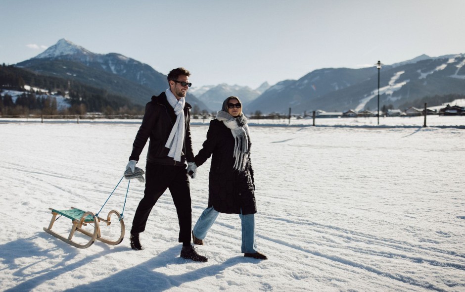 Paar beim romantischen Winterspaziergang mit Schlitten in Flachau
